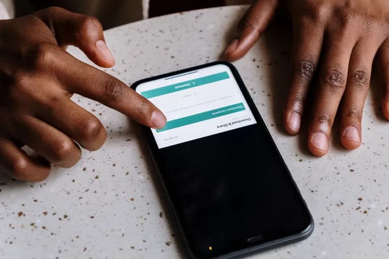 Sepasang tangan menggunakan telefon pintar, sebuah aplikasi sedang dipasang pada skrin