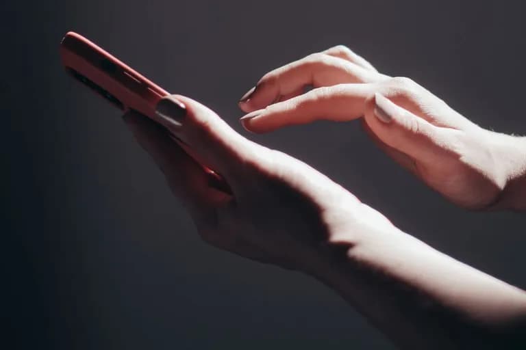 Sepasang tangan di atas telefon pintar yang terletak pada permukaan gelap